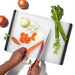 Person chopping carrots on OXO Good Grips Utility Cutting Board