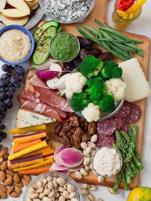 platter of vegetables meats and cheeses on a cutting board